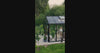 Glass garden greenhouse from PrimeGreenHouses set up as an outdoor lounge, with people relaxing on sofas and chatting together inside.