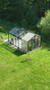 Glass garden greenhouse by PrimeGreenHouses with people relaxing on sofas, enjoying a cozy outdoor living space.